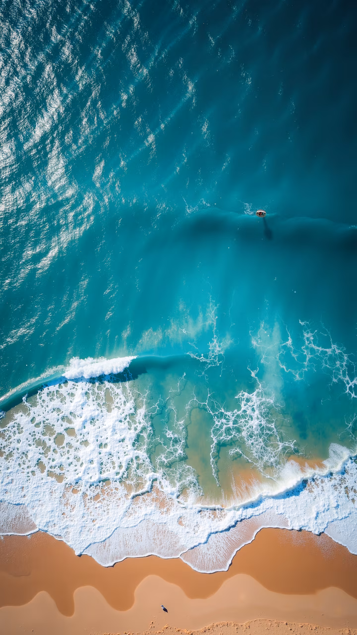 Vibrant turquoise ocean meets sandy beach in this stunning aerial view, capturing the serene beauty of coastal landscapes.