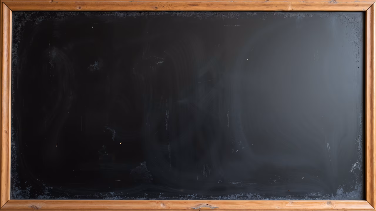 A large, worn chalkboard with faint traces of past writings, framed by rustic wood, evoking nostalgia and history in an educational setting.