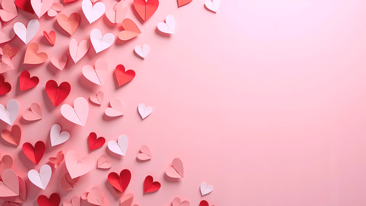 Origami hearts in shades of pink and red on a soft pink background, perfect for Valentine's Day celebrations.