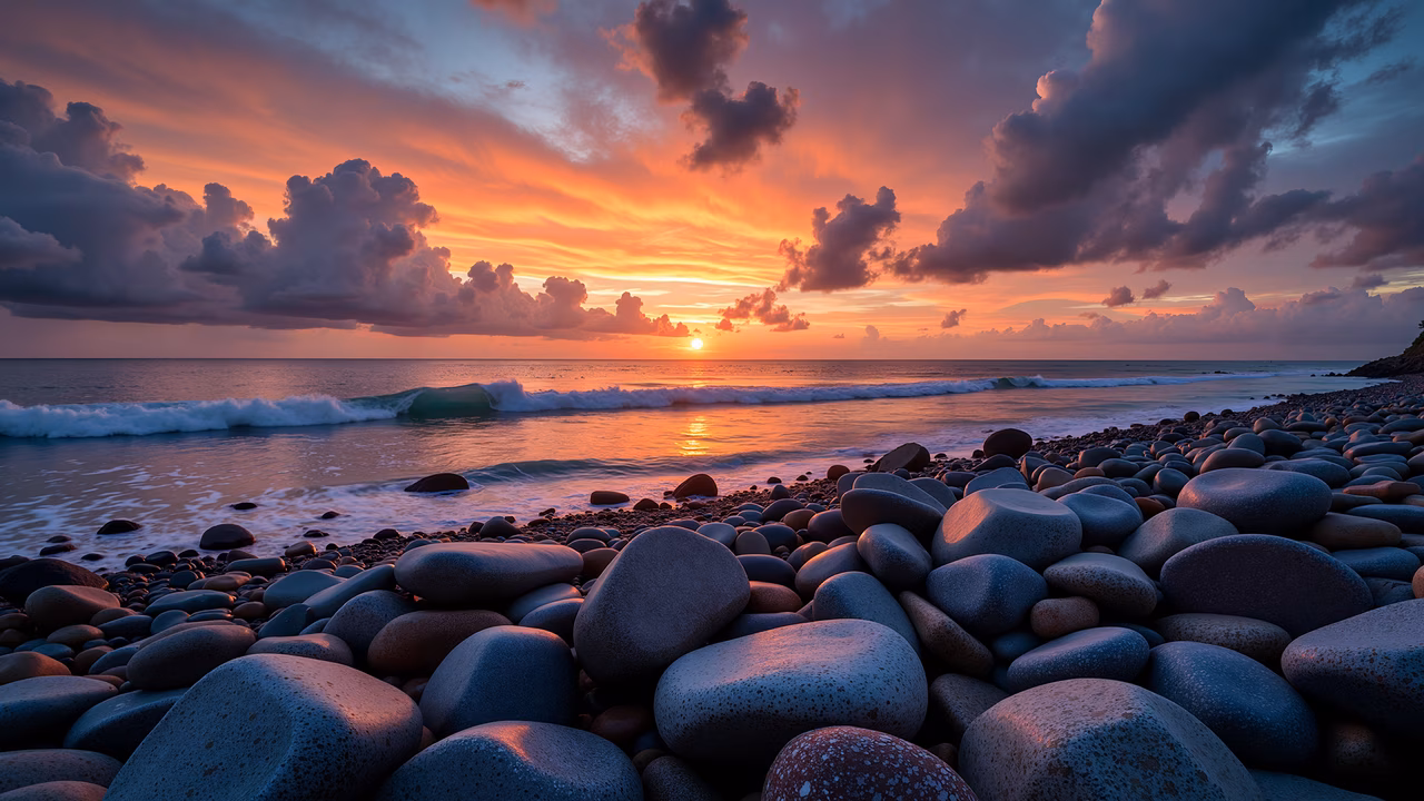 A stunning sunset over a rocky beach, featuring vibrant colors and smooth stones.