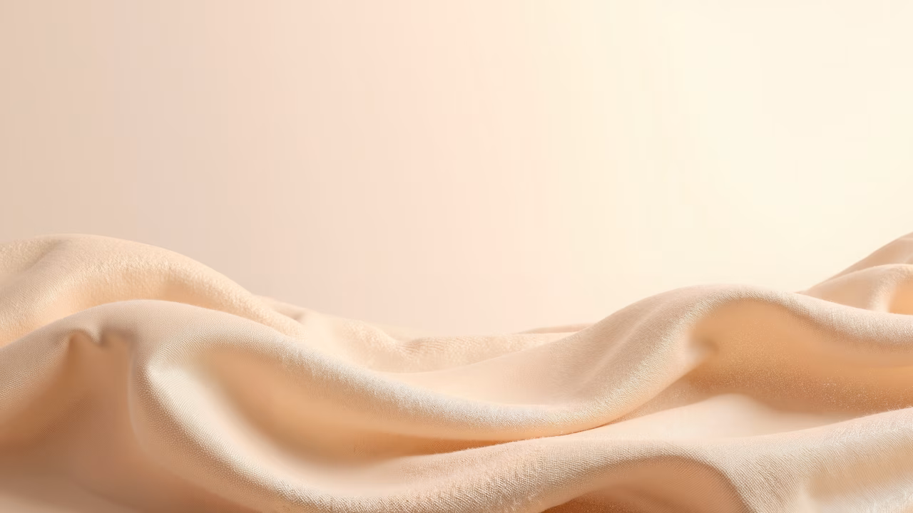 Close-up of silky fabric with warm beige tones and elegant texture.