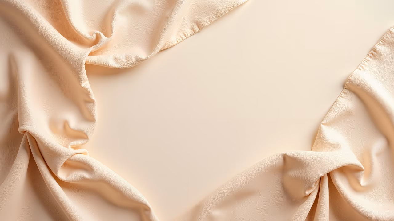 Close-up of silky fabric with soft folds and warm beige tones.