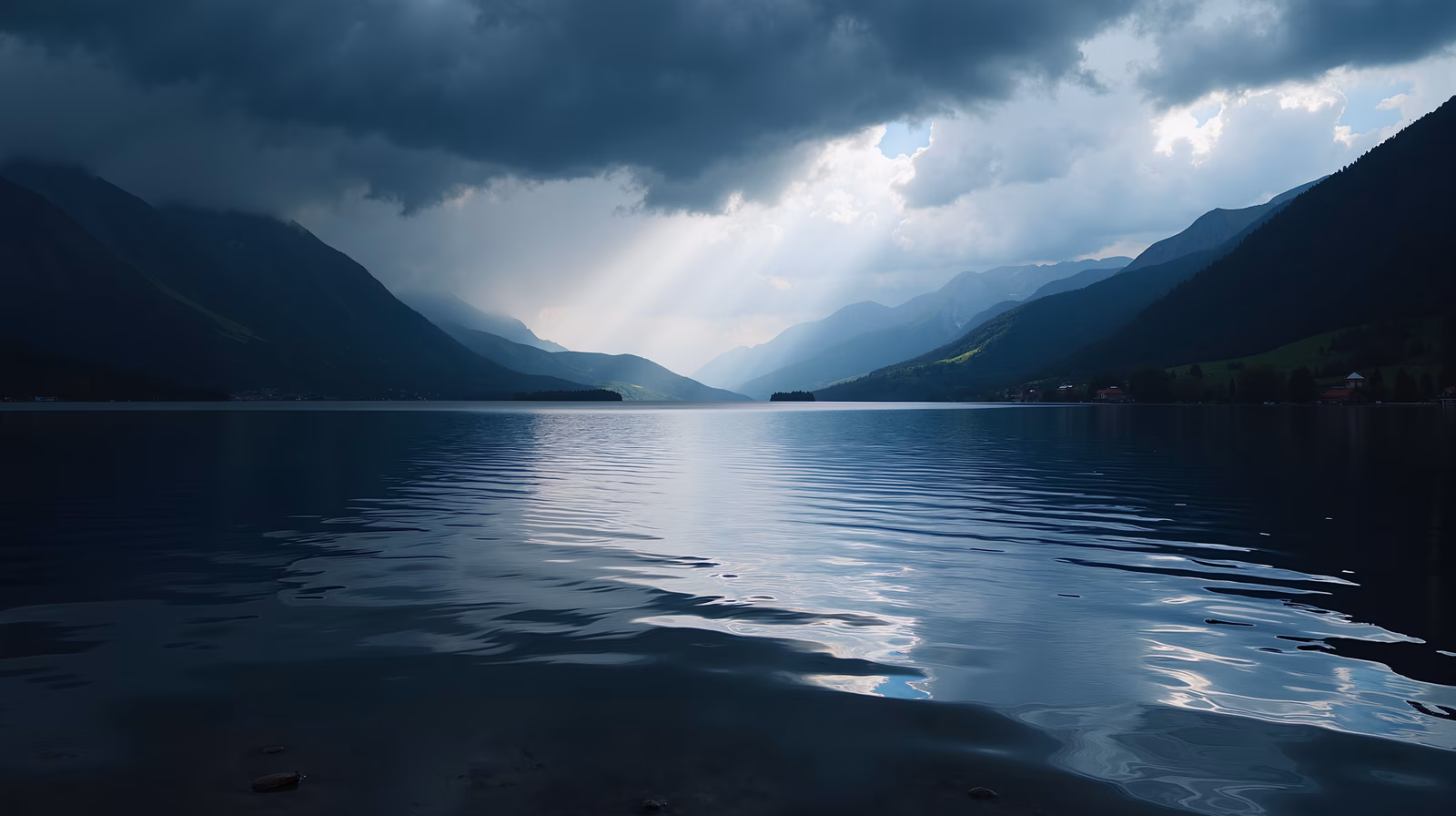 Dramatic sky meets tranquil lake, reflecting mountainous landscape.