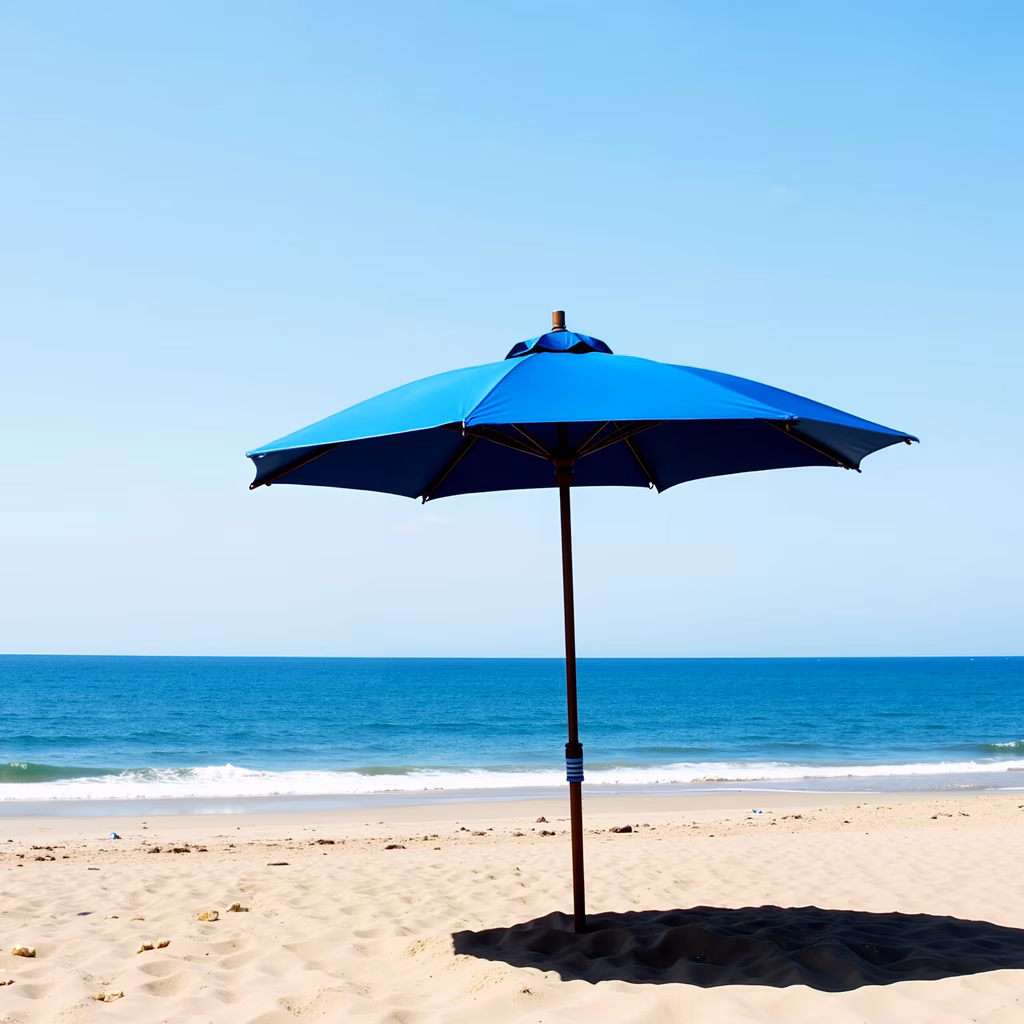 A solitary beach umbrella casts a shadow on the sand, overlooking the ocean.