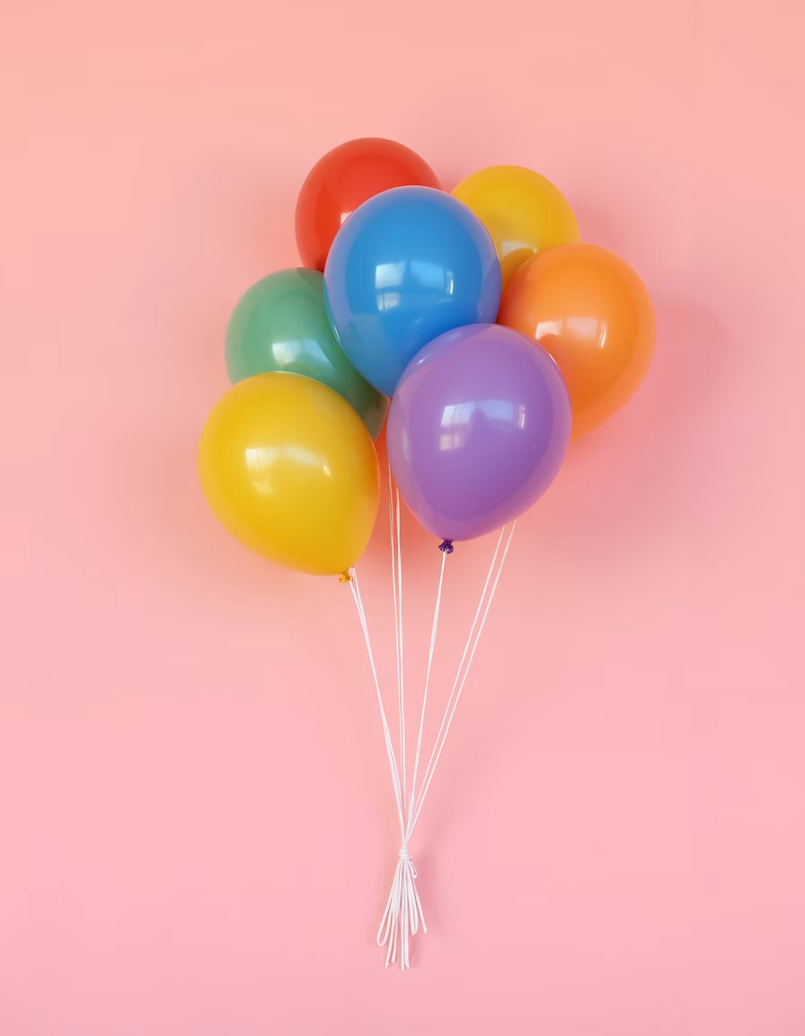 Brightly colored balloons against a pink background, celebrating joy and festivity.
