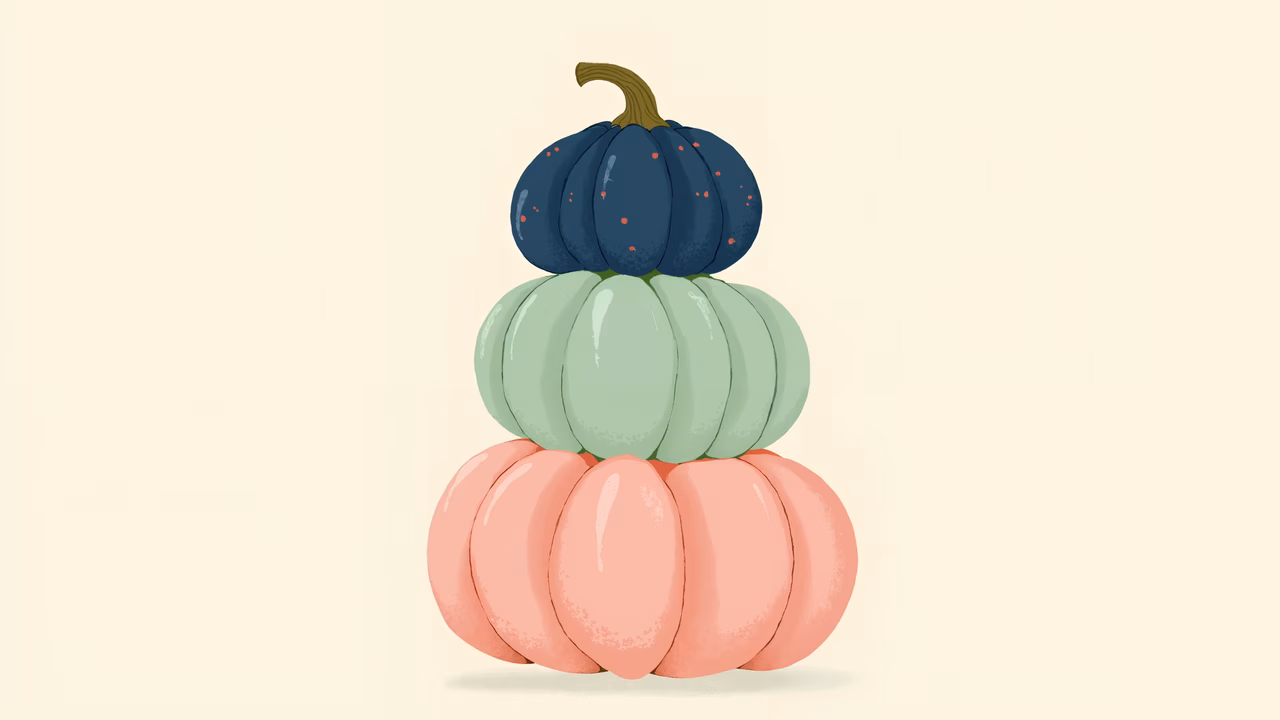 A stack of three colorful pumpkins on a neutral background.