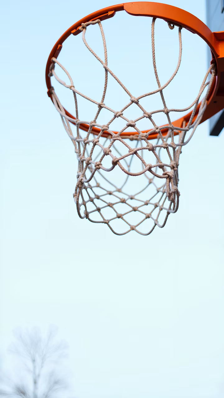 Close-up of a basketball hoop under a clear sky, emphasizing sports and outdoor activities.