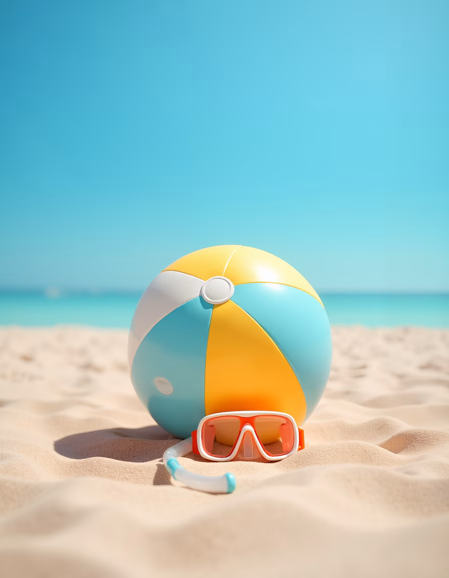 Vibrant beach ball and goggles on sandy beach under clear sky.