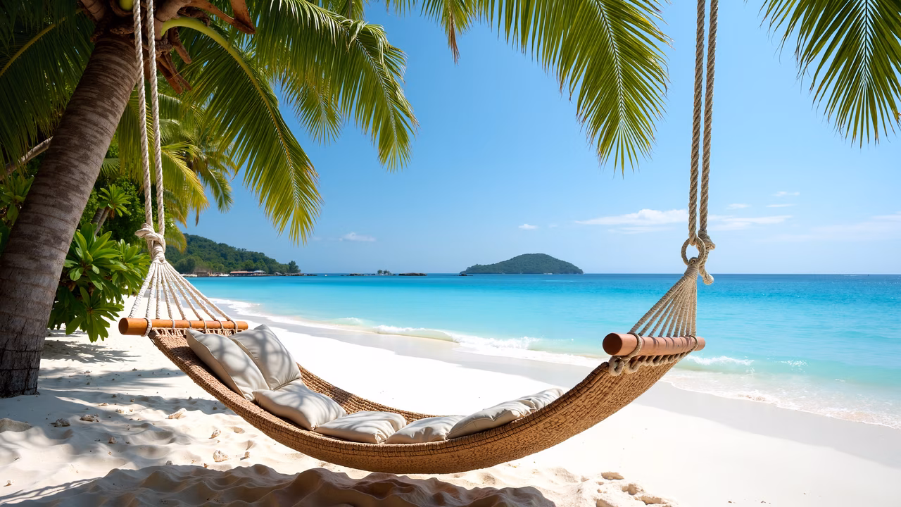 Relaxing beach hammock under palm trees, turquoise waters, and a clear blue sky.