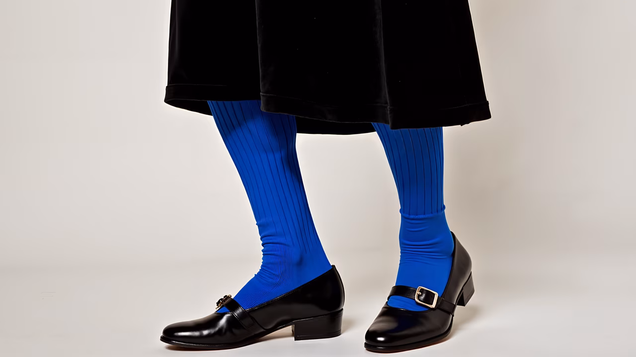 Bold blue socks paired with classic black loafers in a minimalist setting.