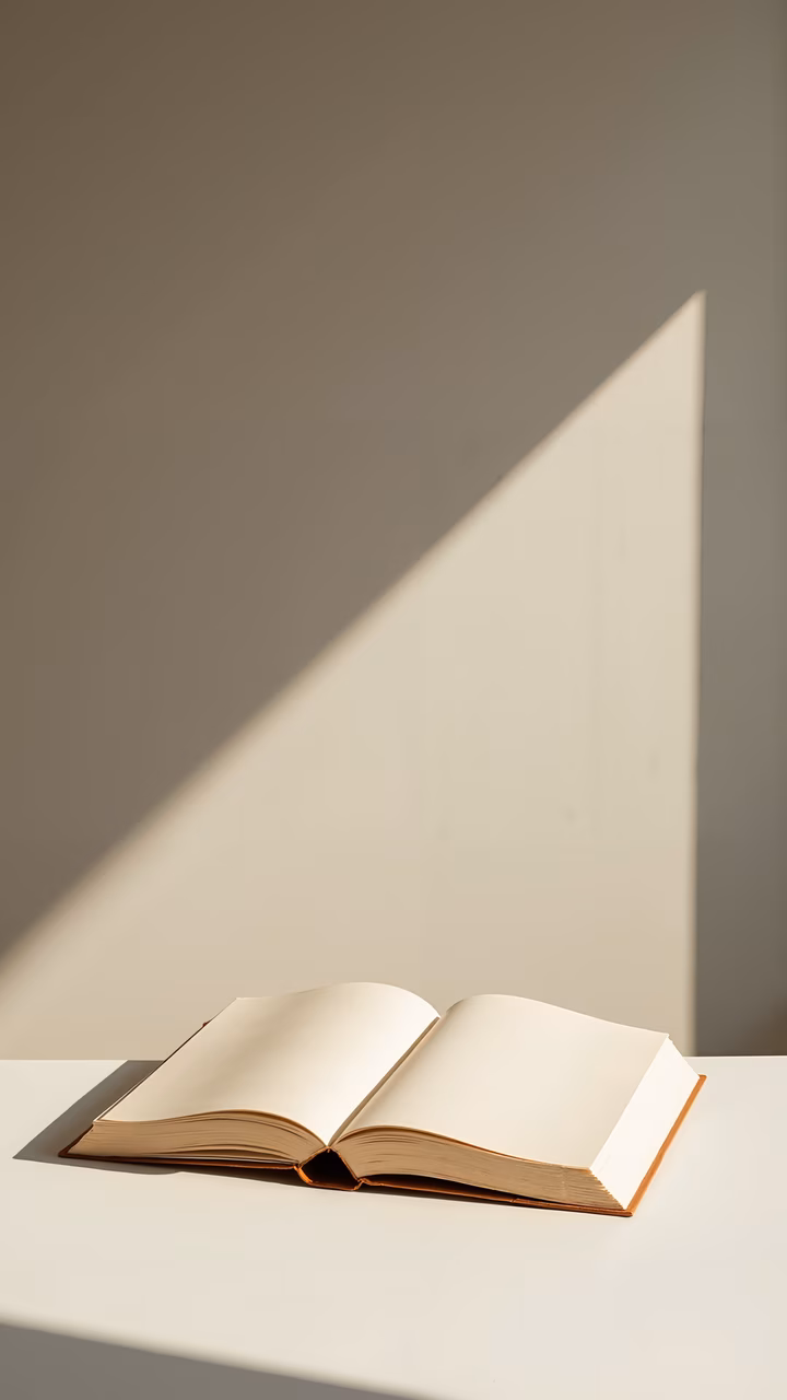 Minimalist photograph of an open book with a triangular shadow, evoking curiosity and simplicity.