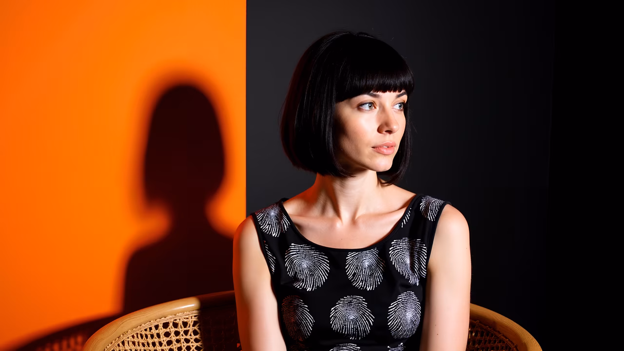 Dramatic portrait with contrasting orange and black backgrounds, highlighting the subject's shadow.