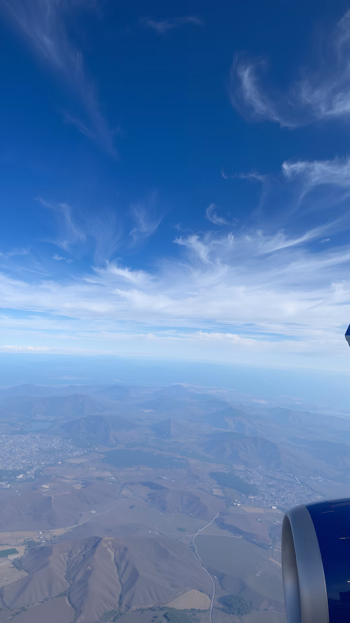 A serene aerial shot of mountains and fields from an airplane window.