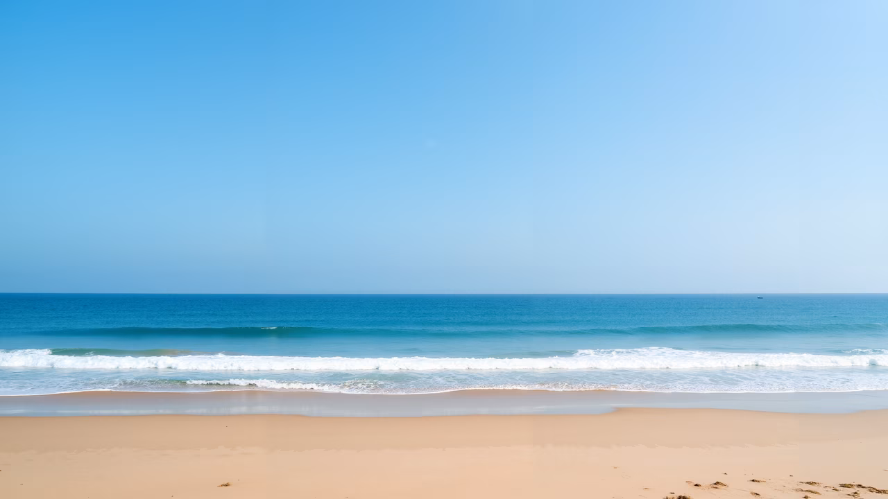 A serene beach with soft waves and clear skies.