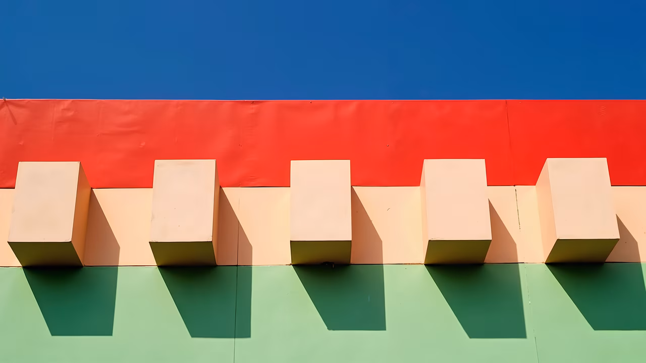 Geometric cubes against a colorful backdrop under a clear blue sky.