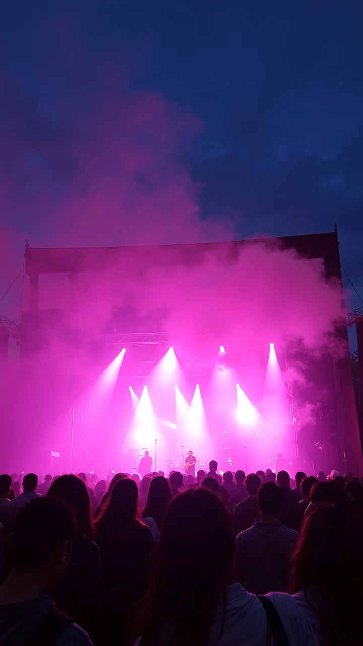 Dynamic concert scene with vibrant purple and pink lighting and a lively crowd.