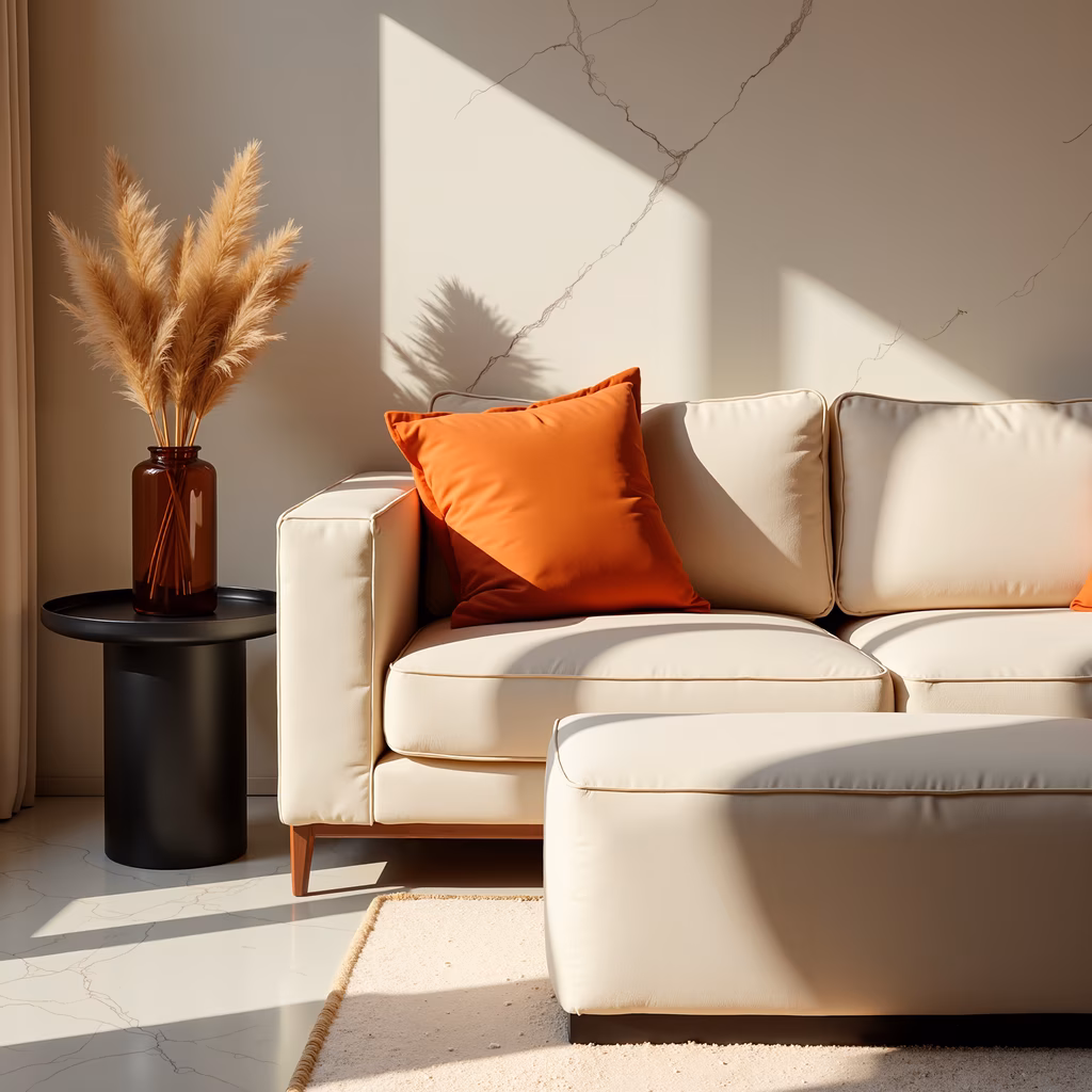 Sunlit interior with cream sofa and orange cushion, minimalist design, natural light, cozy atmosphere.