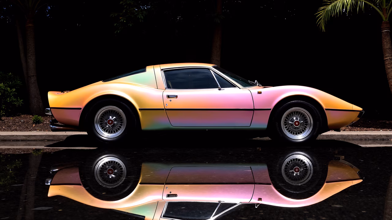 Vibrant holographic classic car reflected in wet surface under palm trees.