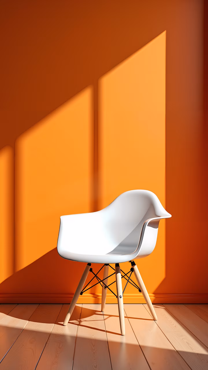 Minimalist white chair against vibrant orange wall, bathed in natural light.