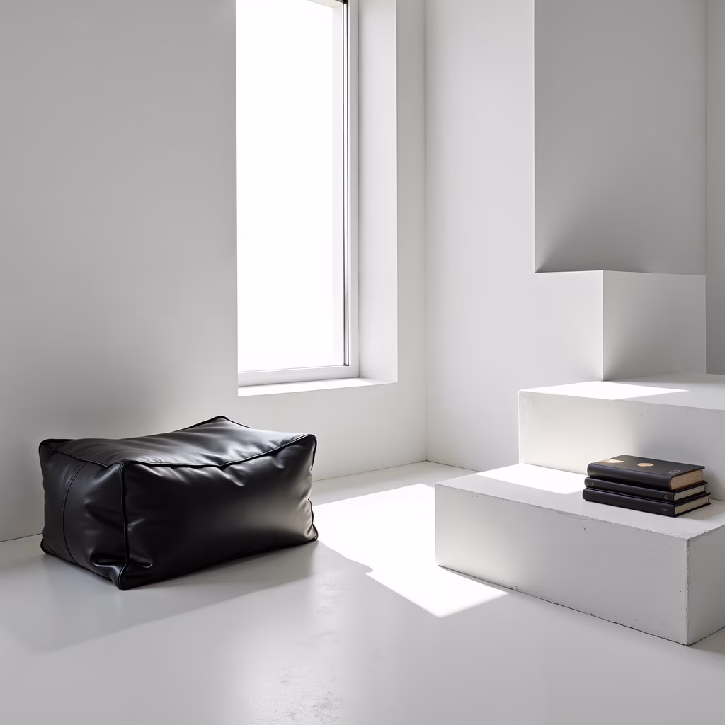 Modern minimalist interior with black pouf and white concrete bench.