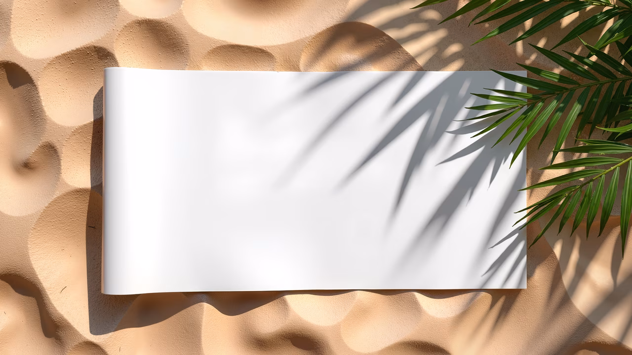 A blank sheet of paper on textured sand, bathed in warm light, creating a serene and inviting atmosphere.