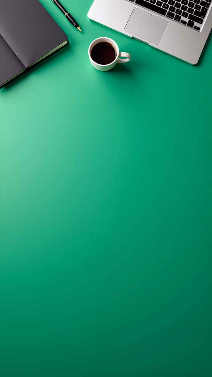 Minimalist desk setup with notebook, pen, laptop, and coffee cup on a green background.