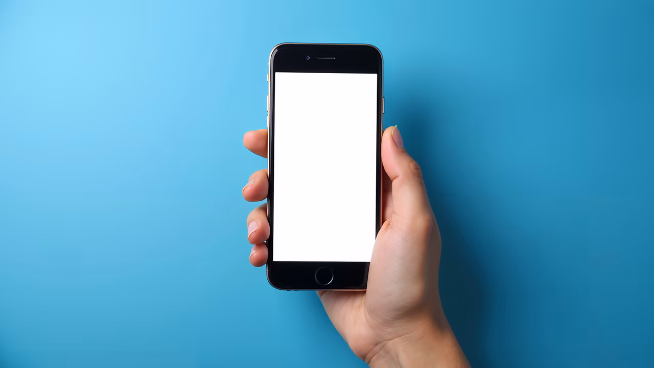 Close-up of a hand holding a blank-screen smartphone against a turquoise background.