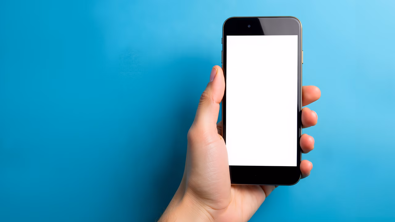 Close-up of hand holding smartphone against turquoise background.