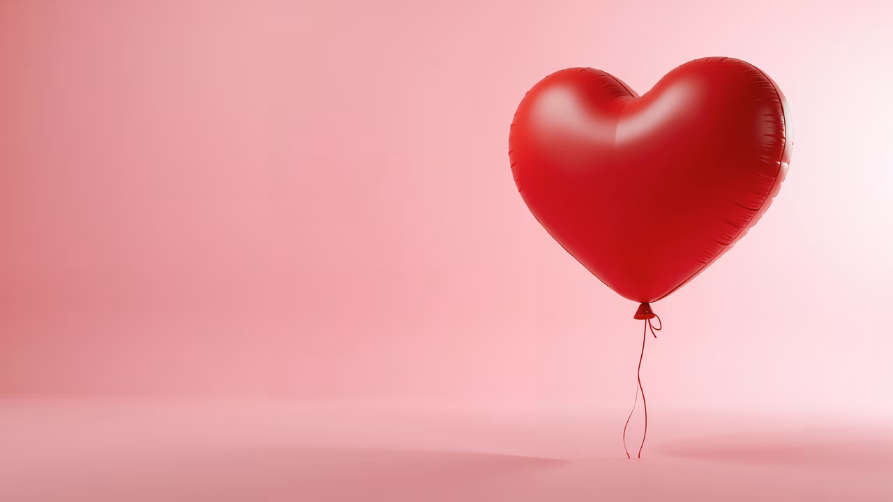 Vibrant red heart balloon against a soft pink gradient backdrop, symbolizing love and Valentine's Day.
