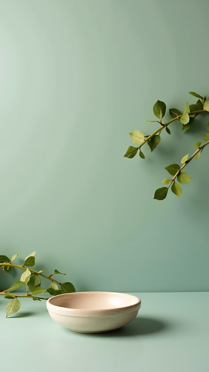 Simple beige bowl with green leaves against a soft green background.