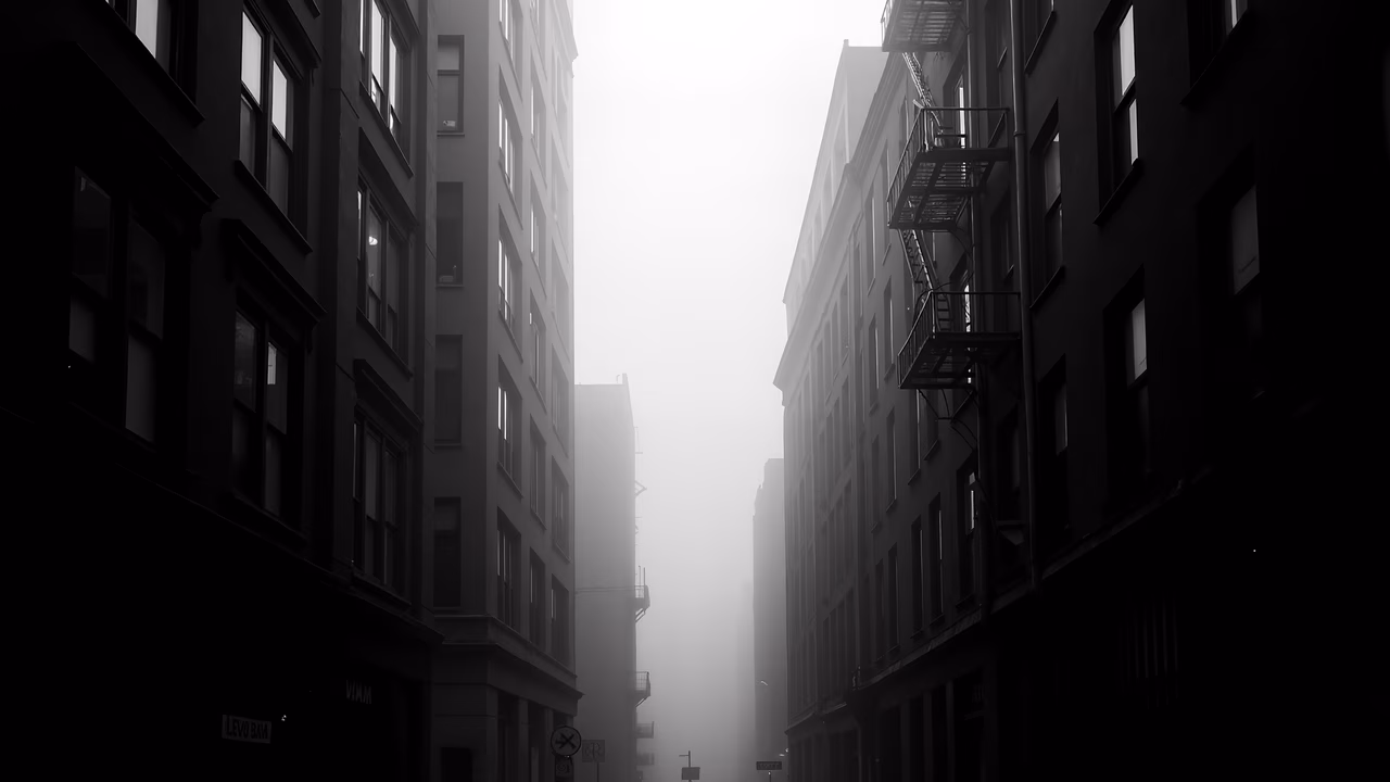 A hauntingly quiet alleyway enveloped in fog, captured in black and white.