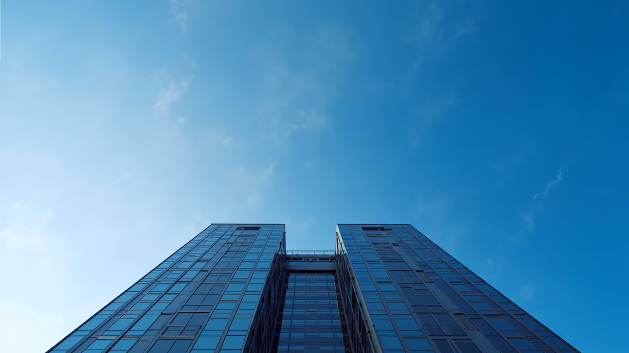 Modern skyscrapers reflecting sunlight against a clear blue sky.