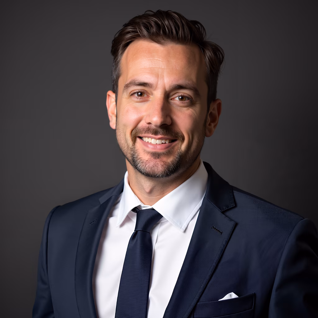 Professional headshot of a man in formal attire against a neutral backdrop.