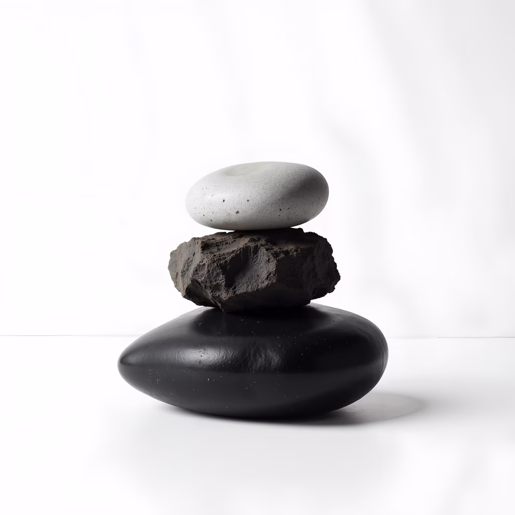 Minimalist still life photography featuring balanced stacked stones against a white backdrop.