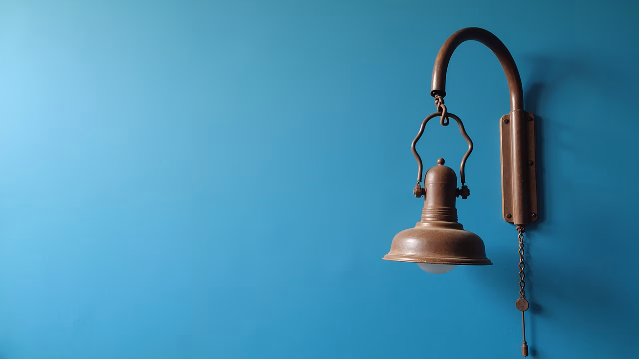 Vintage wall light fixture against a teal background, evoking warmth and nostalgia.