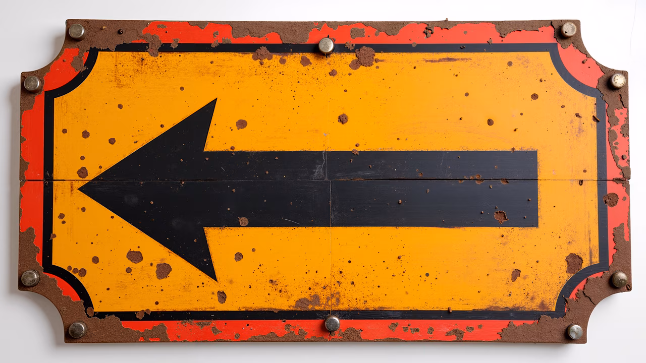 A weathered directional sign with a bold black arrow on a vibrant yellow background.