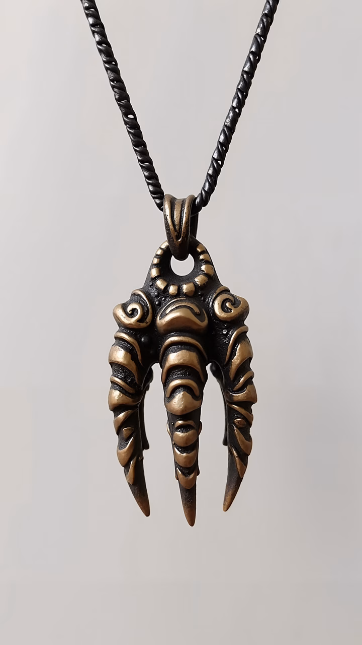 Detailed alien claw pendant with metallic gold and bronze finish, dark and mysterious design.