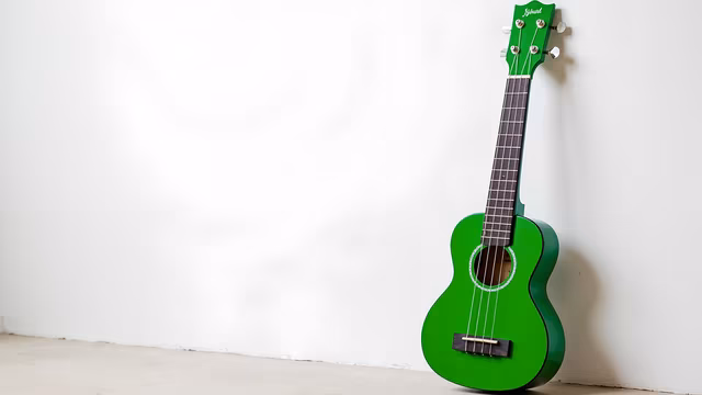 Green Ukulele Against White Wall