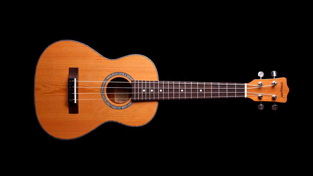Close-up of an acoustic guitar with natural wood finish against a black background.