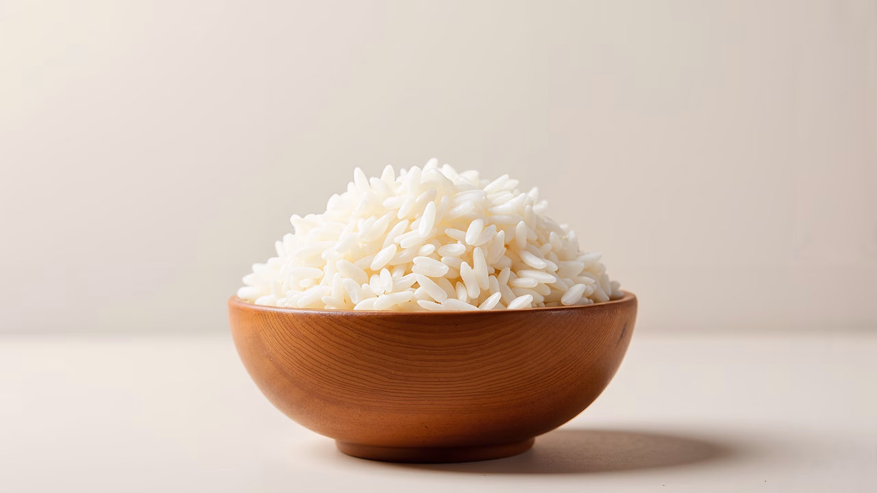 Close-up photo of fluffy white rice in a wooden bowl, neutral background, soft lighting.