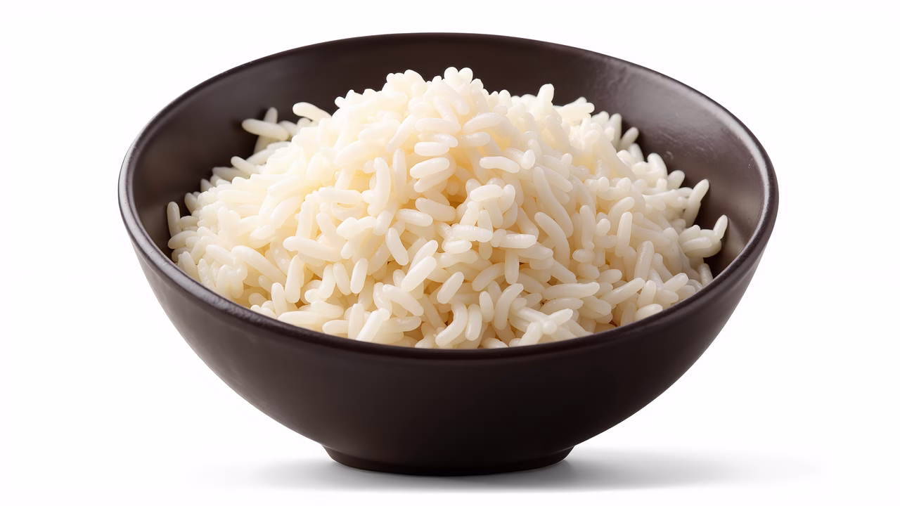 Close-up of a bowl of fluffy white rice in natural light, emphasizing texture and simplicity.