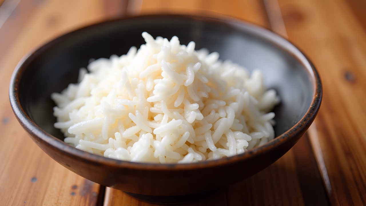 Close-up of fluffy white rice in a bowl on a wooden table.