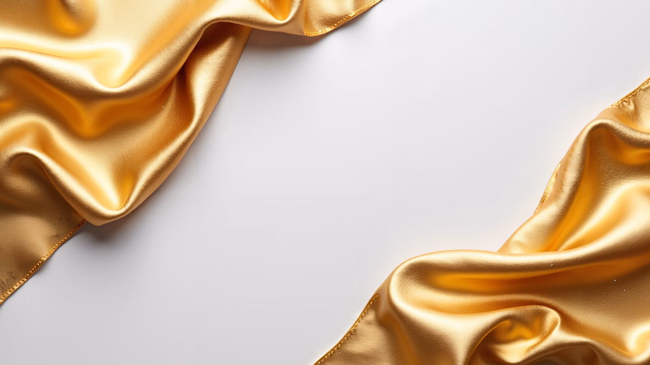 Luxurious golden silk fabric framed against a white background, emphasizing elegance and opulence.