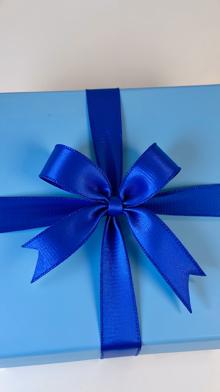 Close-up of a light blue gift box with a royal blue ribbon bow.