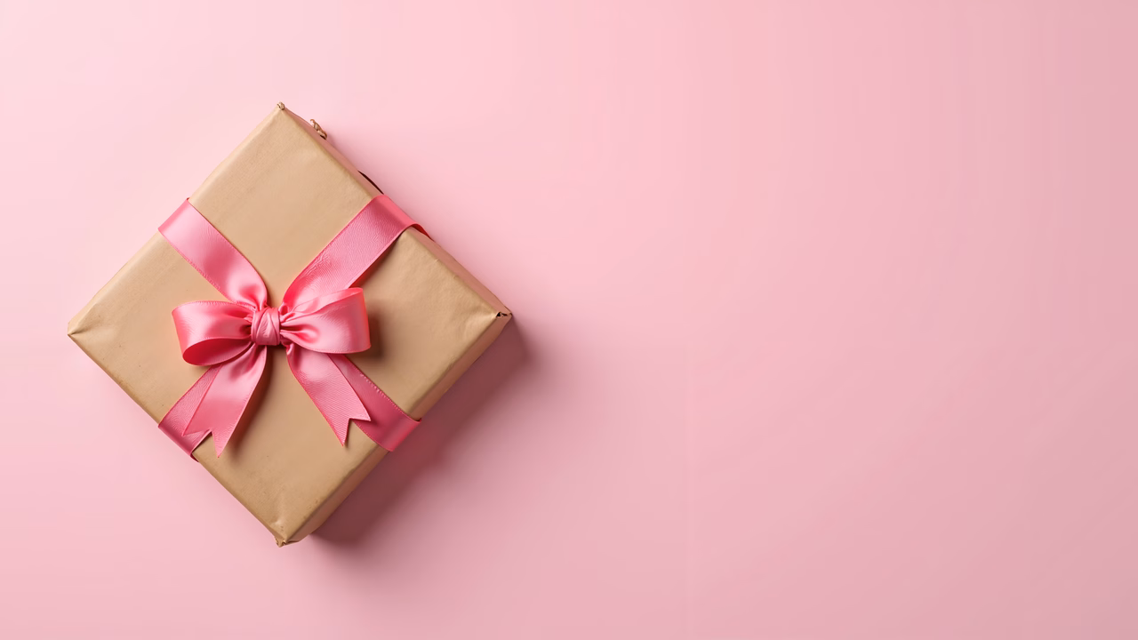A festive gift box with a pink ribbon on a pink background.