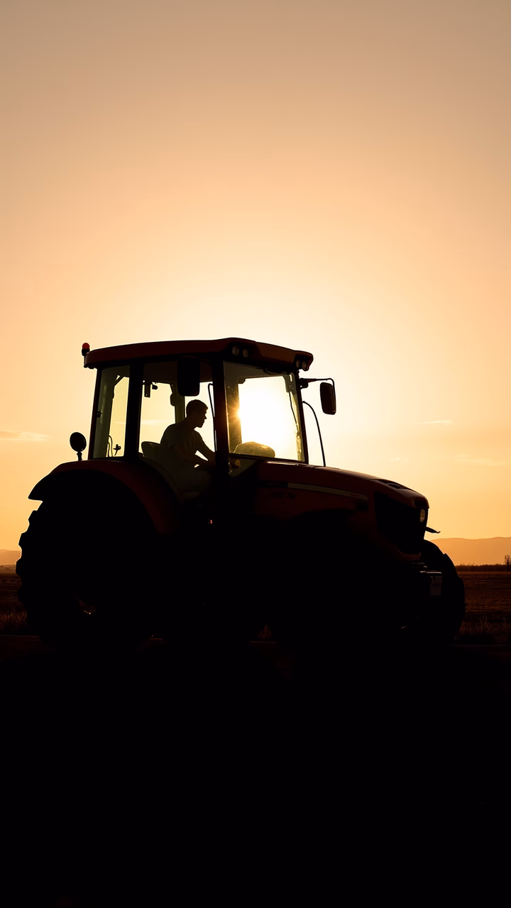 Silhouetted tractor against a stunning sunset, symbolizing rural tranquility.