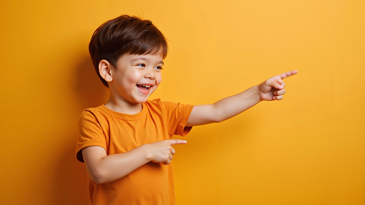 Cheerful young boy pointing excitedly in a bright yellow portrait.