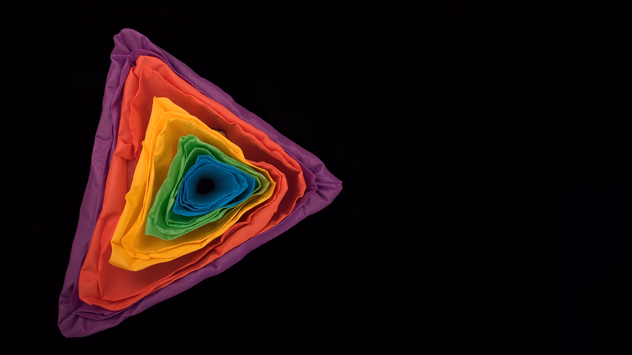 Vibrant rainbow triangle with textured fabric layers on a black background.