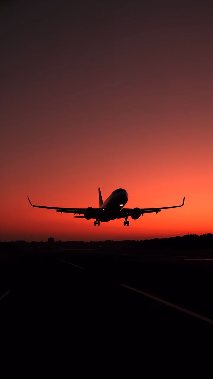 Silhouette of an airplane taking off against a vibrant sunset sky, symbolizing travel and adventure.