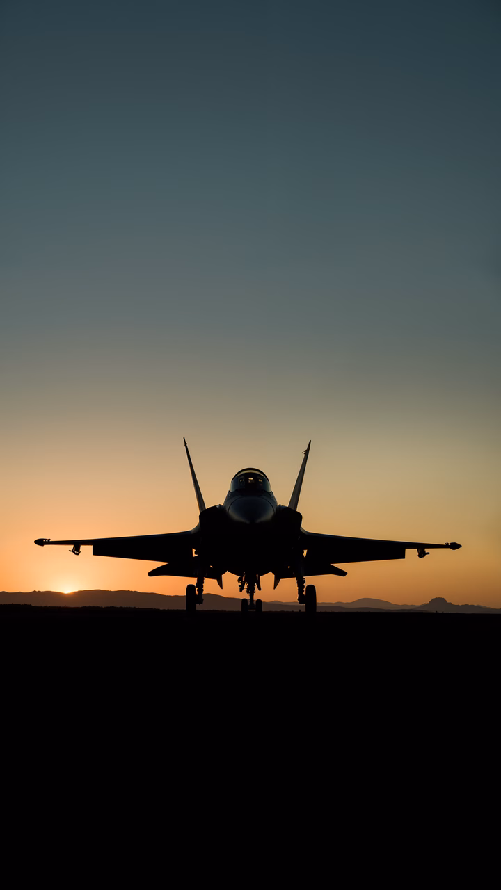 Silhouette fighter jet on runway at sunset, showcasing military aviation and serene beauty.